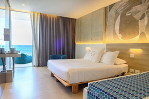 Quarto de hotel moderno com uma cama grande, uma escrivaninha e vista para o mar.