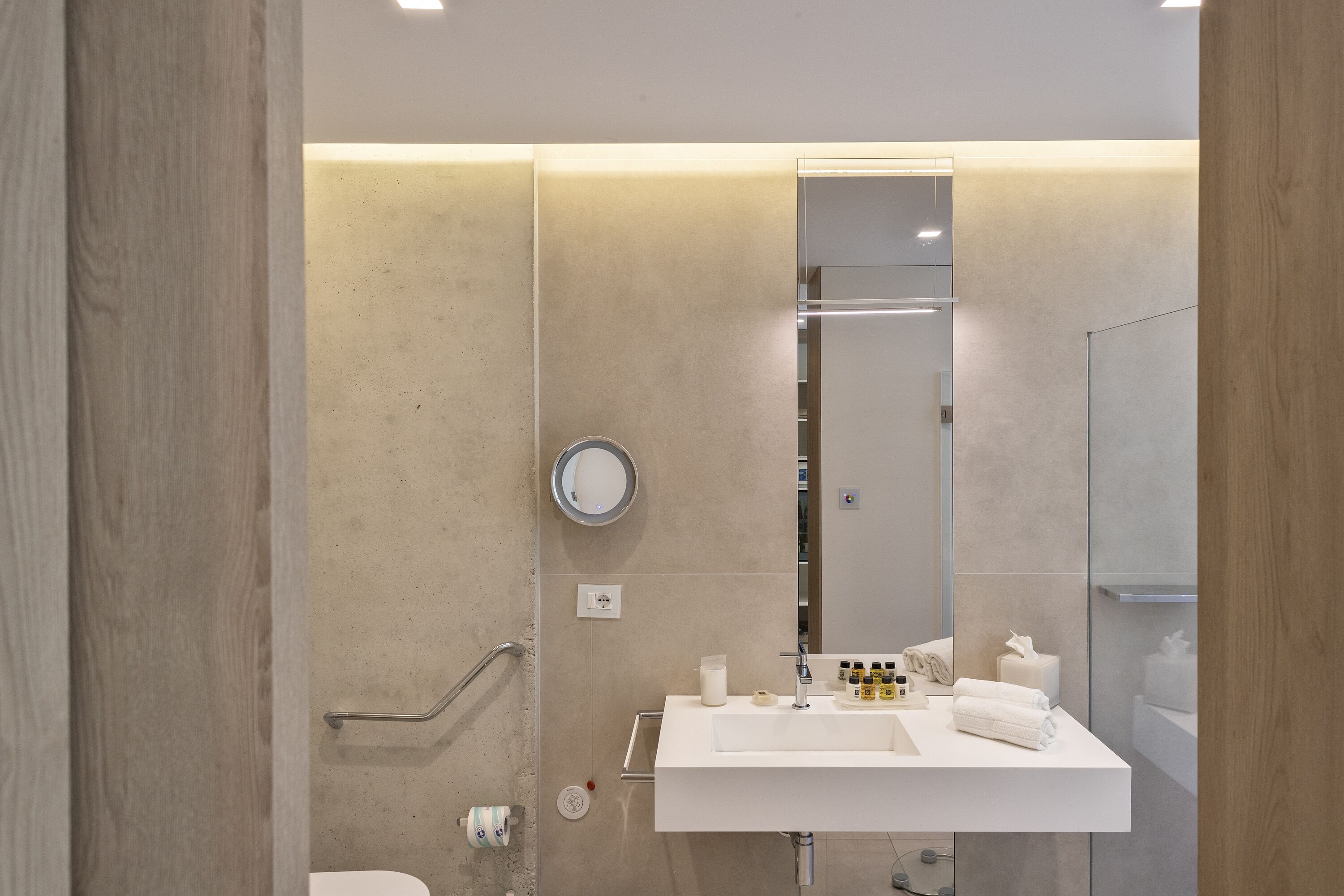 A modern bathroom with a white sink, mirror, and towel rack.