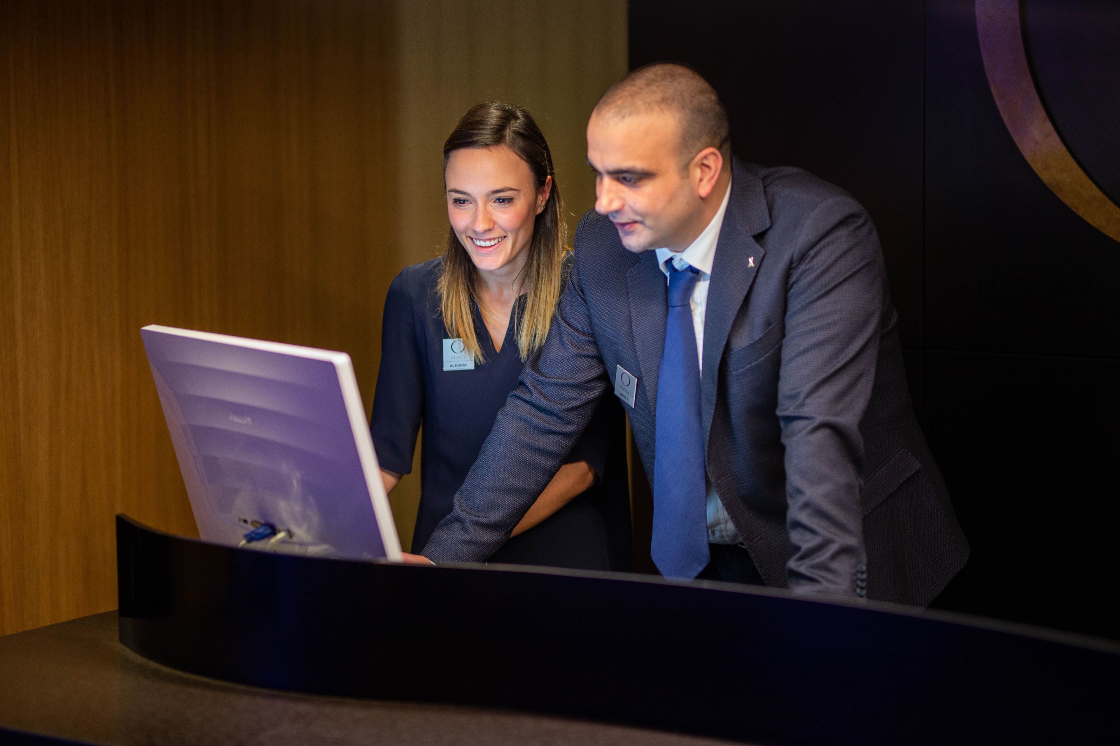 Two people standing at a podium with a laptop.