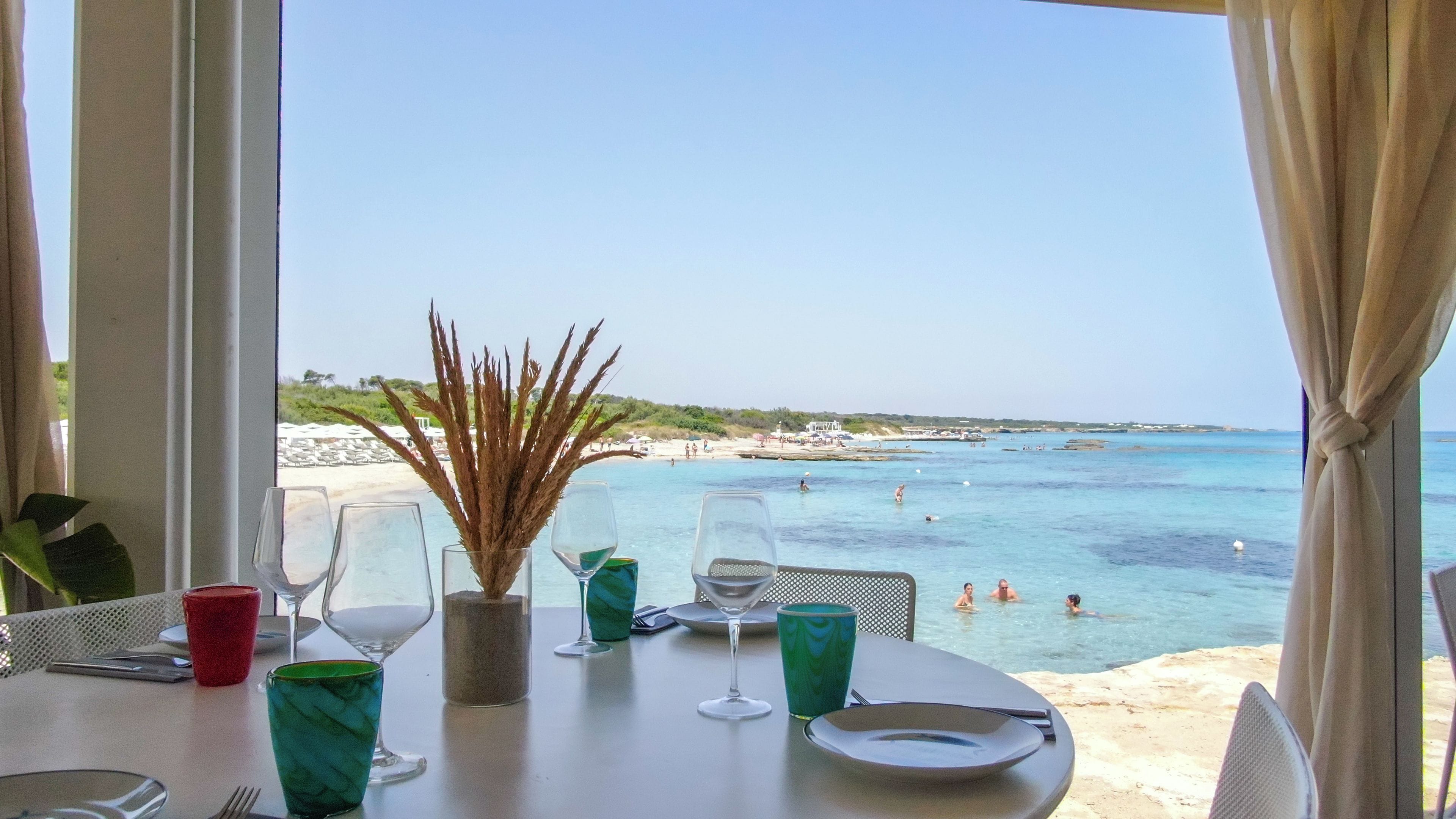 Une table dressée pour le dîner, avec vue sur la plage et la mer.