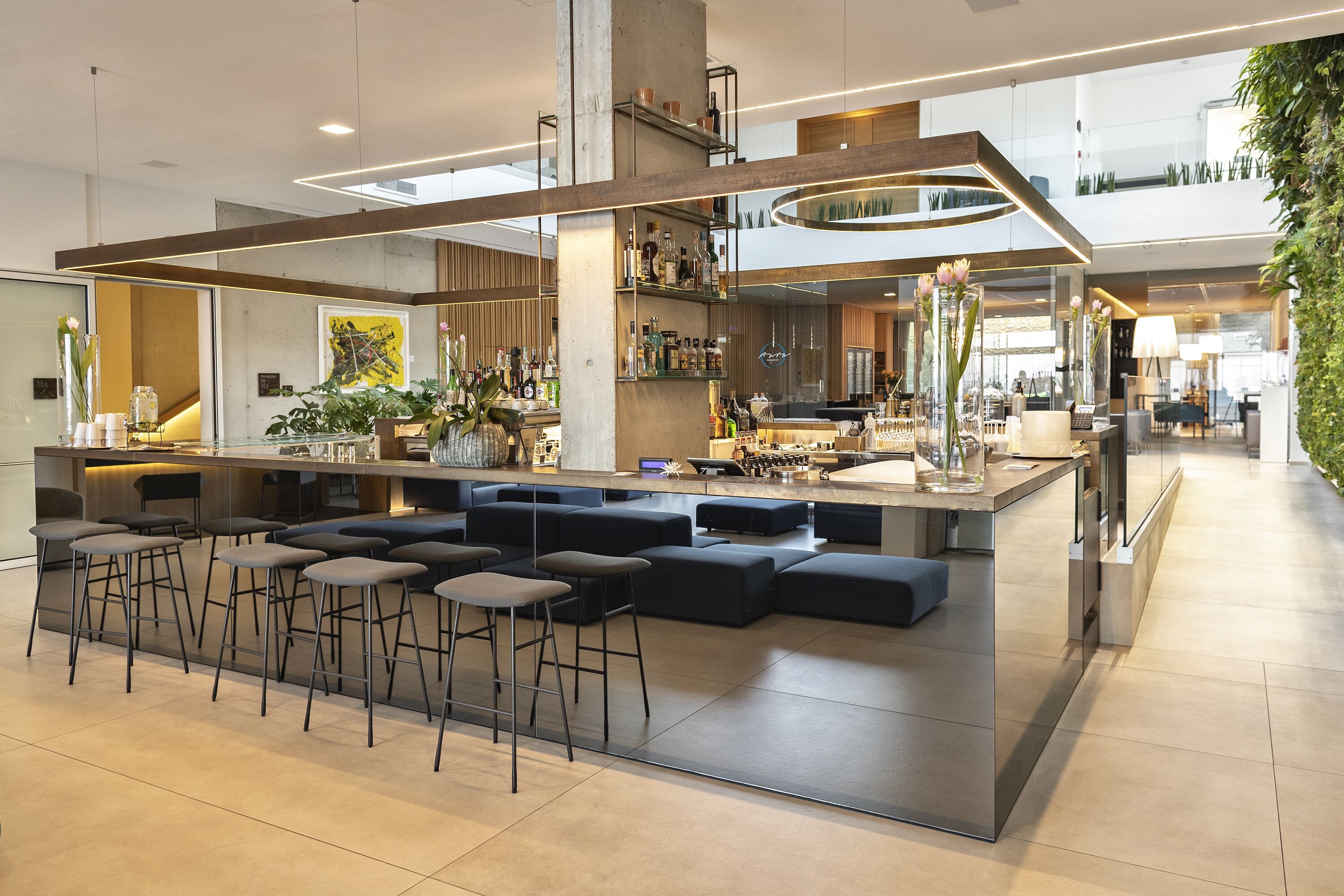 A modern bar area with stools, a bar counter, and a seating area with sofas.