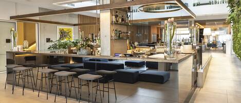 A modern bar area with stools, a bar counter, and a seating area with sofas.