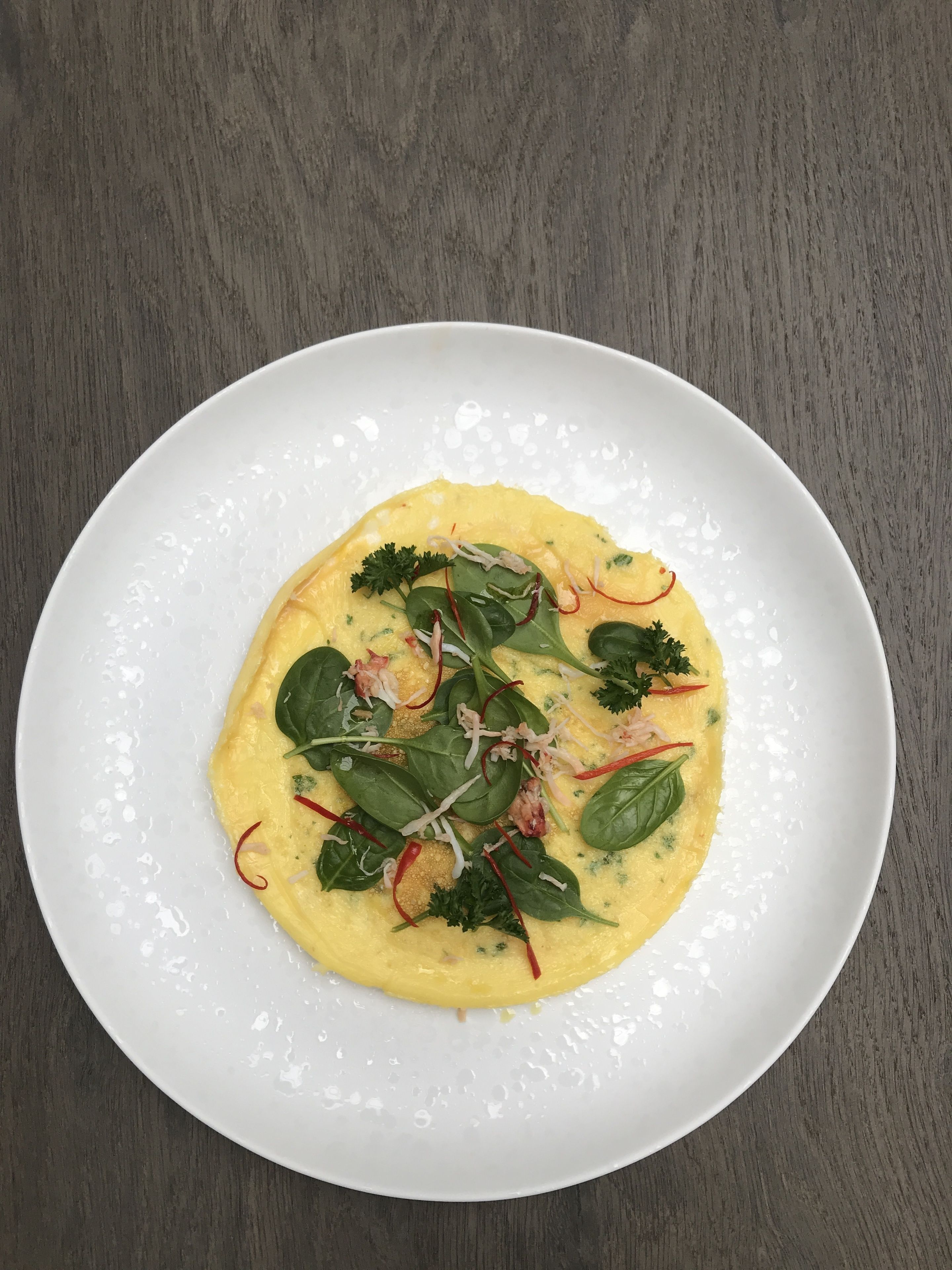 A white plate with a yellow dish on a wooden table.