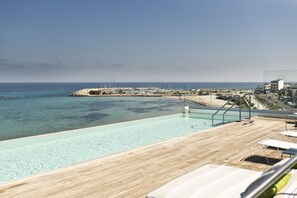 Uma área à beira da piscina com vista para o mar e um porto de iates.
