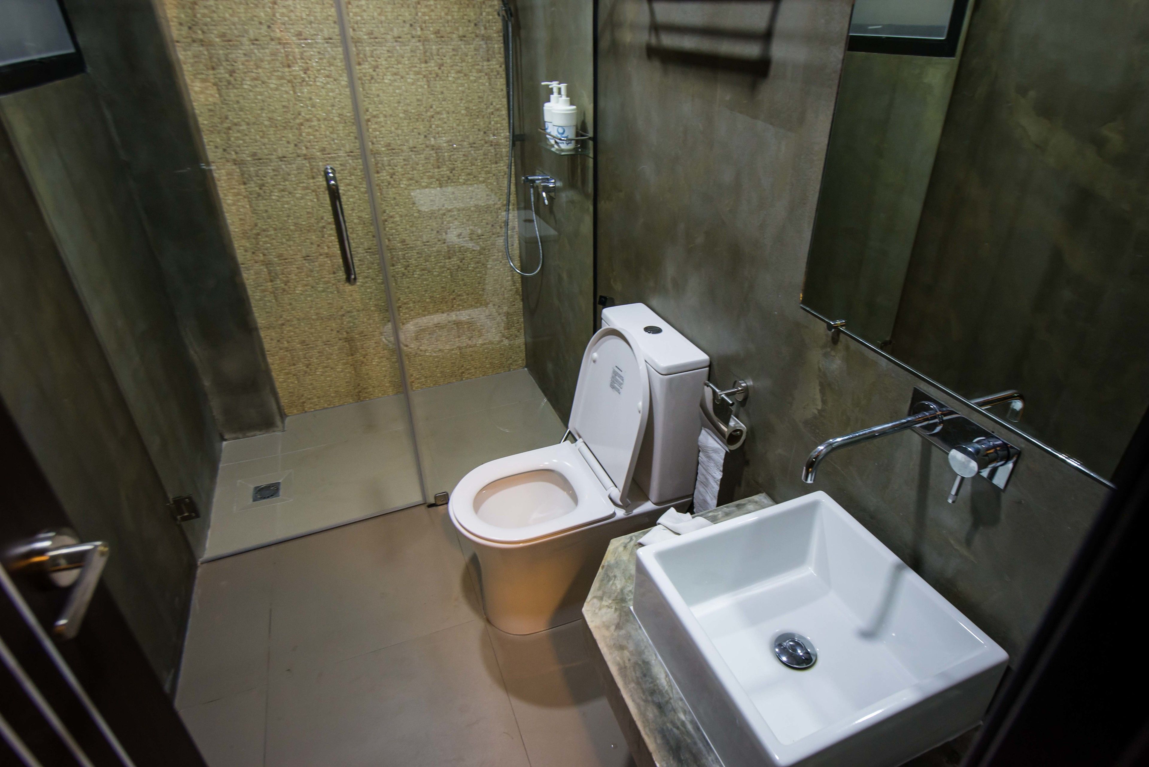 A modern bathroom with a toilet, shower, and sink.