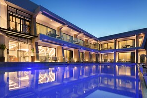 A modern hotel with a large indoor swimming pool, multiple balconies, and contemporary architecture.