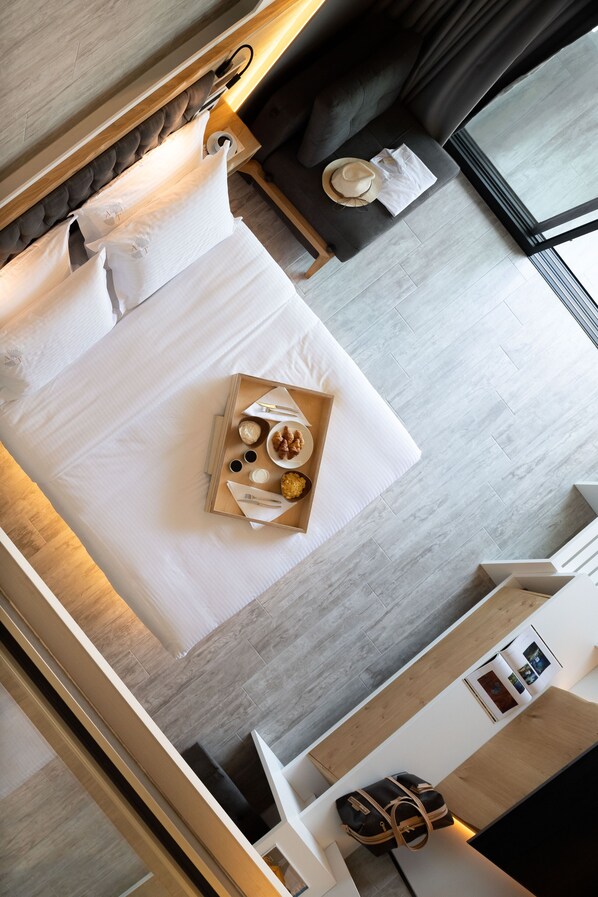 A modern hotel room with a neatly made bed, a tray with breakfast items, a sofa, and a window with curtains. - Akti Toroni Boutique Hotel (Sithonia)