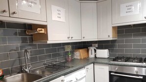 A kitchen with white cabinets, a stainless steel sink, a washing machine, a toaster, and a stove.