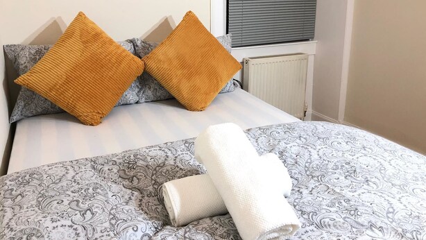 A neatly made bed with patterned bedding and two large, rectangular pillows. - The Dalgety Apartments (Edinburgh)