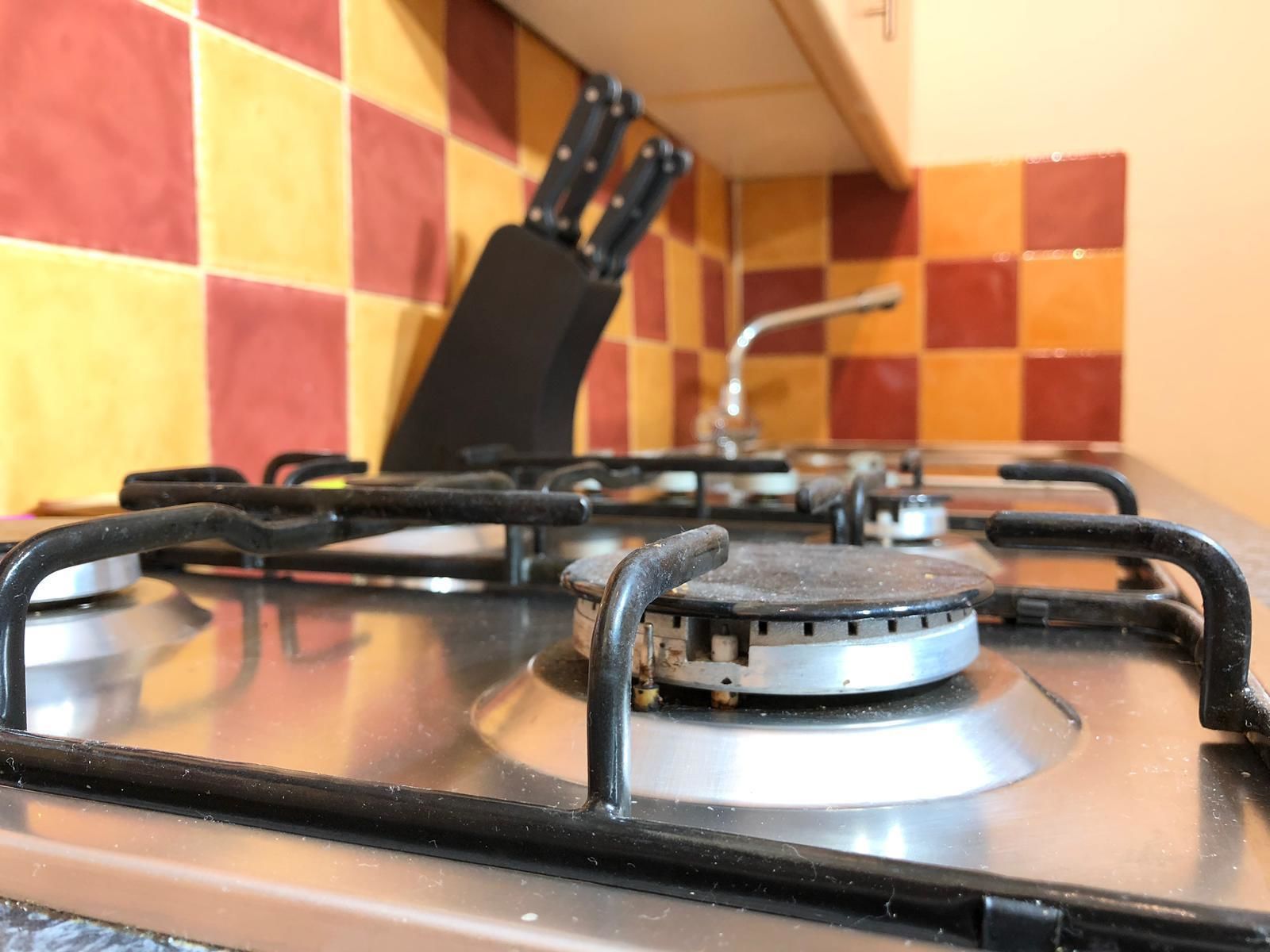 A kitchen with a gas stove, a knife block, and a tiled backsplash.