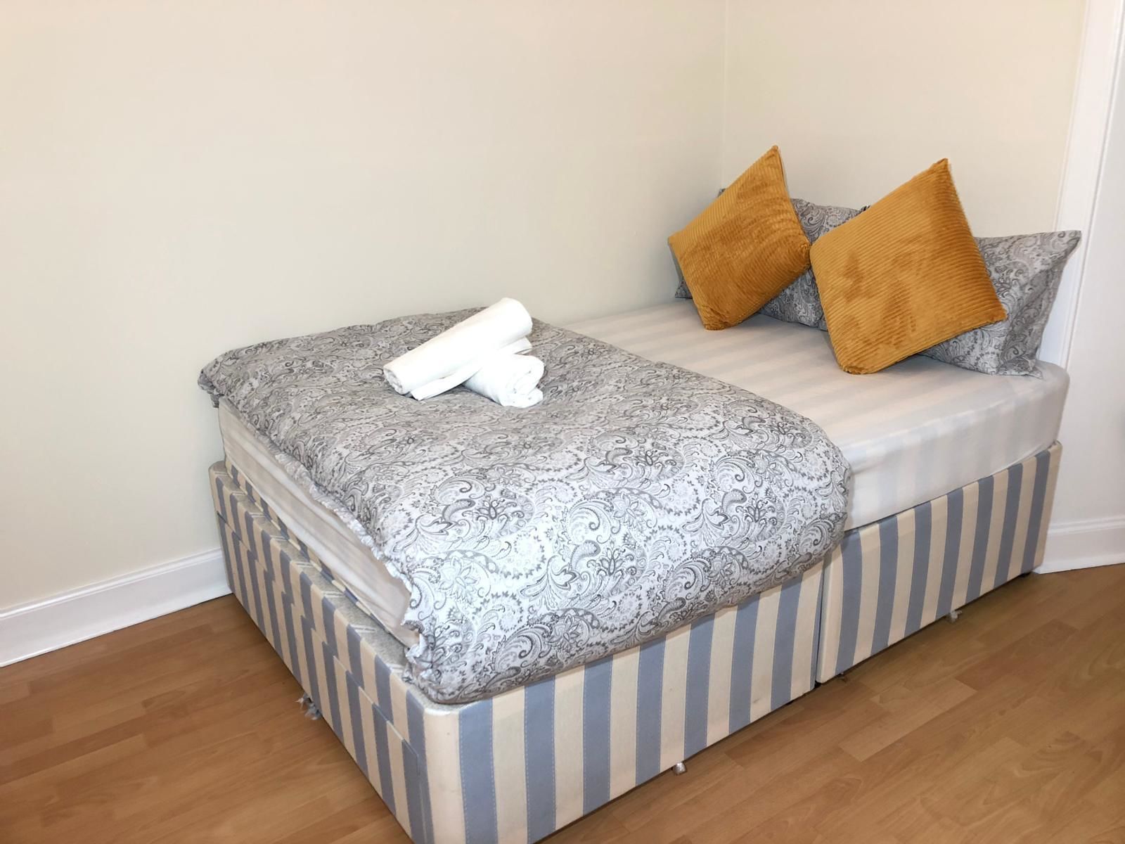 Un lit avec une couvre-lit à motifs, deux oreillers et une serviette enroulée.