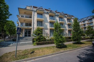 Et hotel med flere etager, altaner, en fodgængerindgang og en velholdt græsplæne.