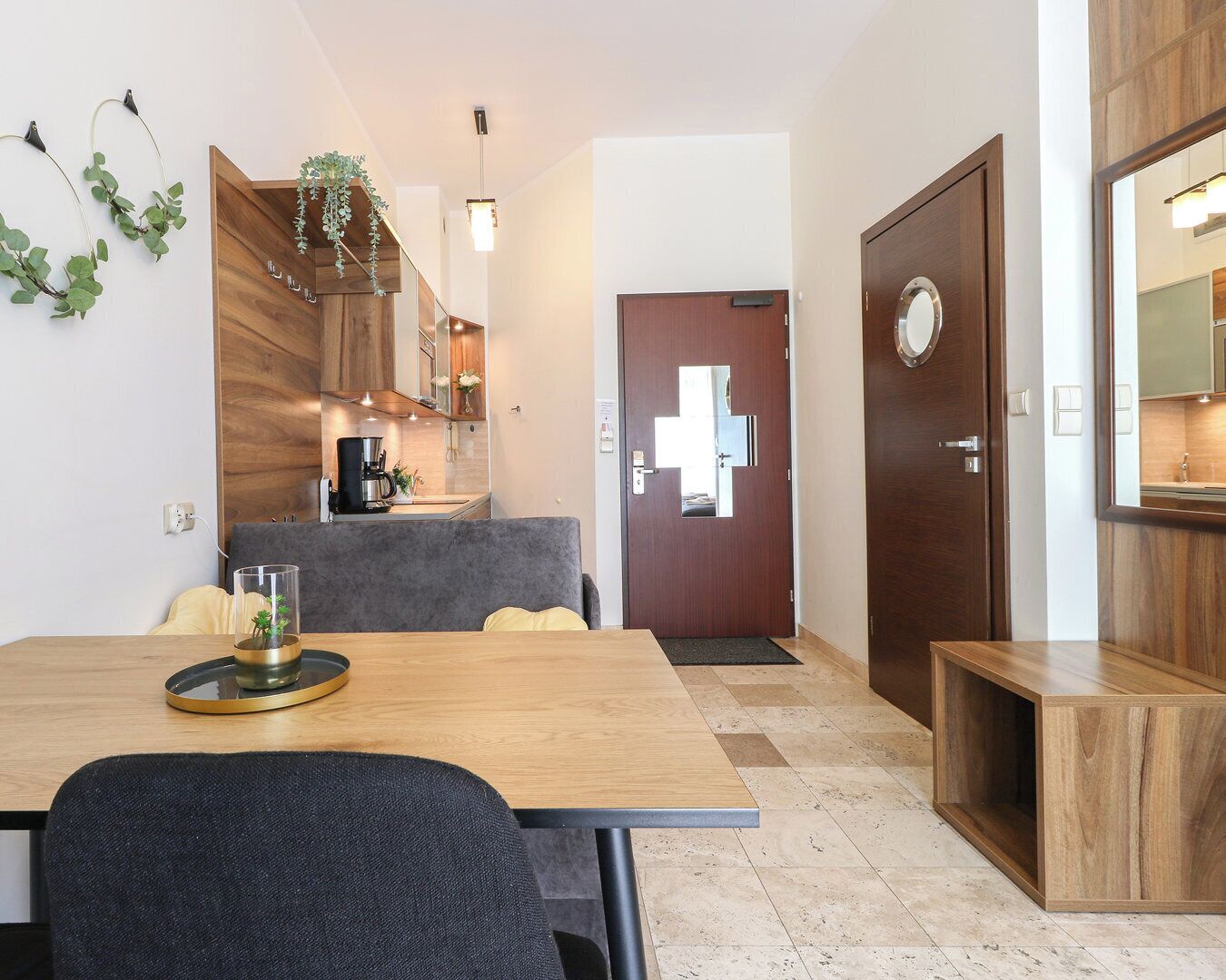 Une cuisine moderne avec des meubles en bois, une machine à café et un coin repas comprenant une table et des chaises.