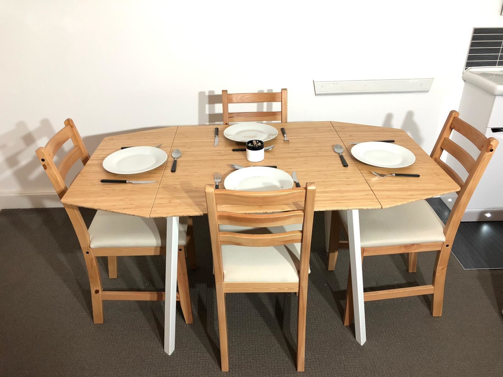 A round wooden dining table with four chairs, each with a cushioned seat.