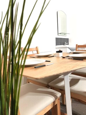 Un coin repas avec une table en bois, des chaises blanches et une assiette blanche.