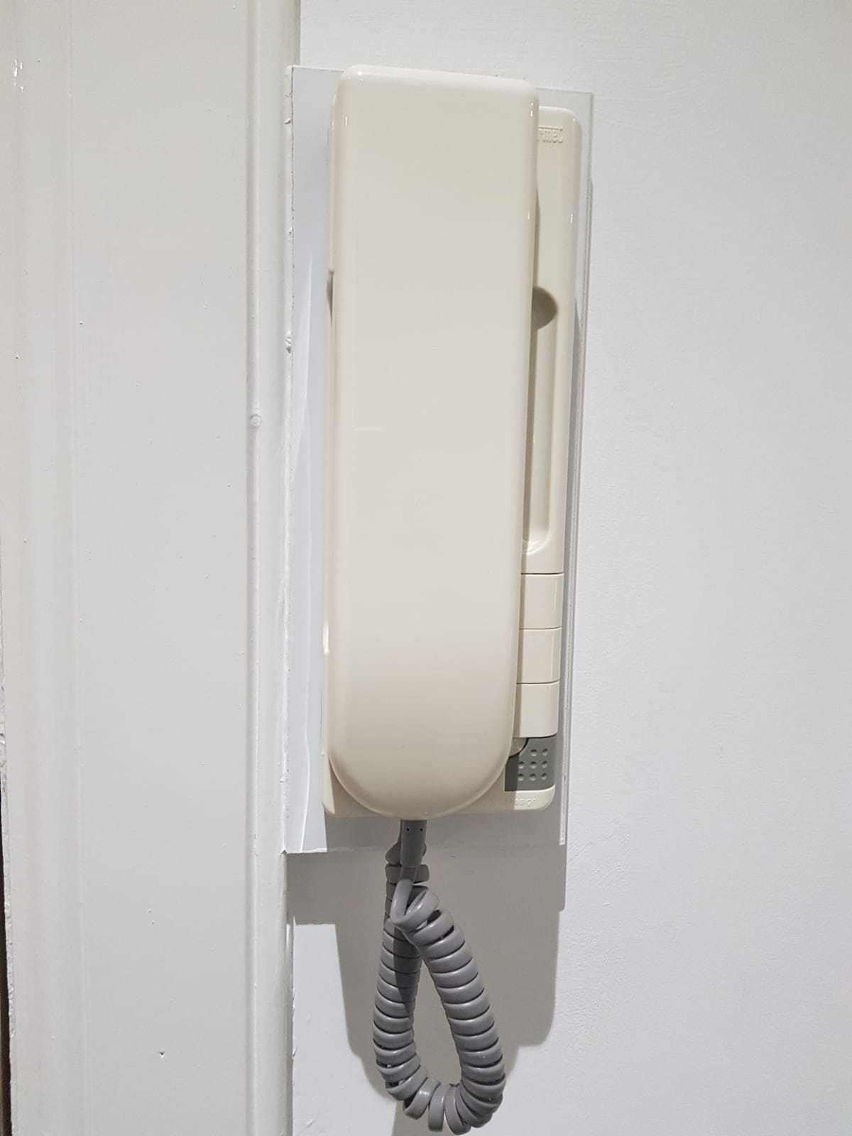A wall-mounted telephone with a coiled cord.