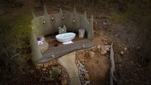 Et spa-område med en stor stenskum, stearinlys og en træterrasse.