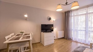 A modern living room with a dining table, a flat-screen TV, and a sofa. - Rosa Weneda by Baltic Home (Swinoujscie)
