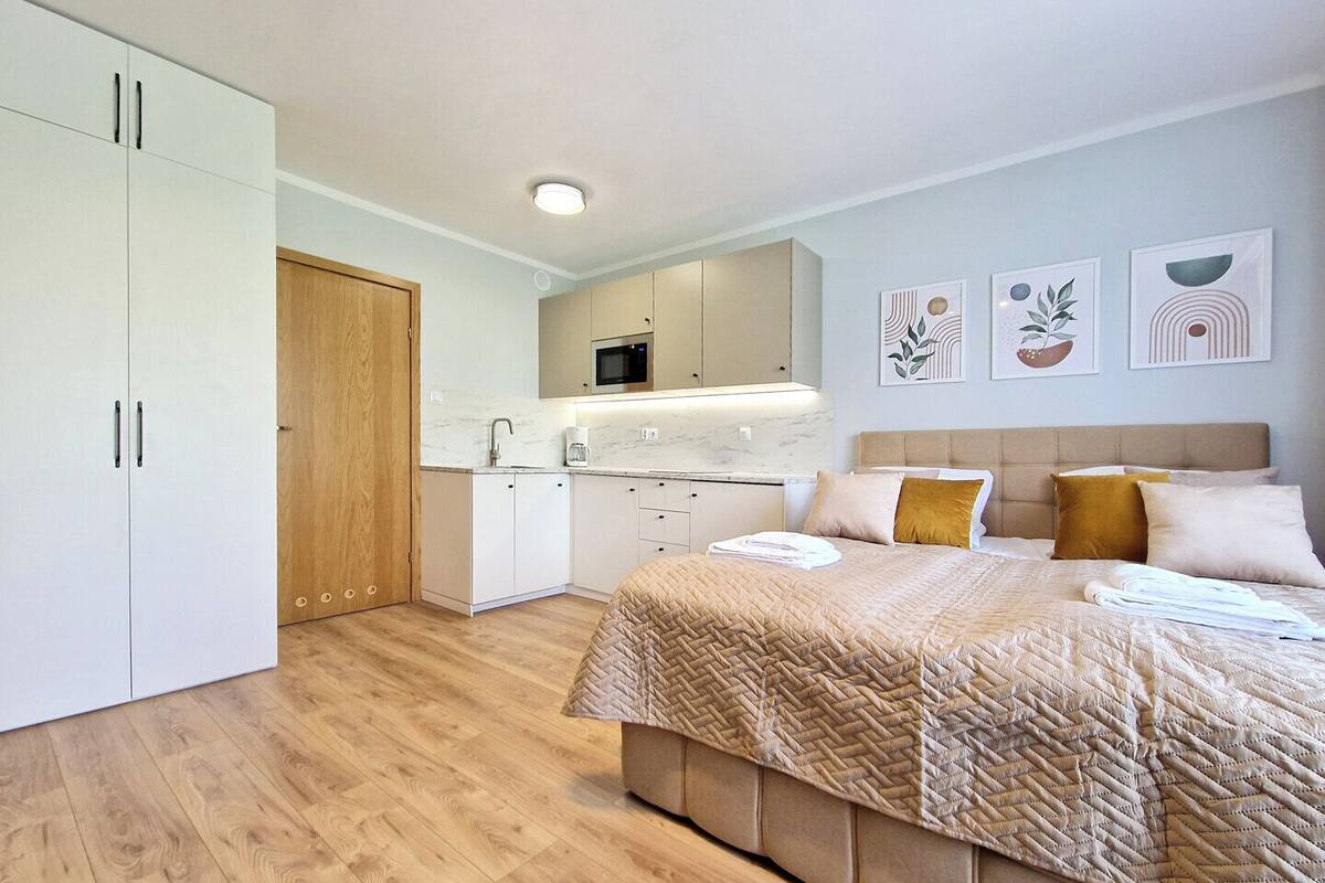 Een moderne slaapkamer met een groot bed, een inbouw kast, een keukenhoek en een badkamer.