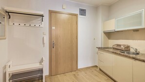 A compact kitchen with a wooden door, a built-in microwave, and a sink with a beige countertop. - Rosa Weneda by Baltic Home (Swinoujscie)
