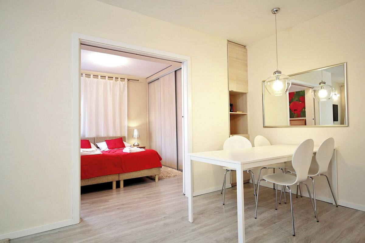 A bedroom with a bed, a bedside table, and a mirror.