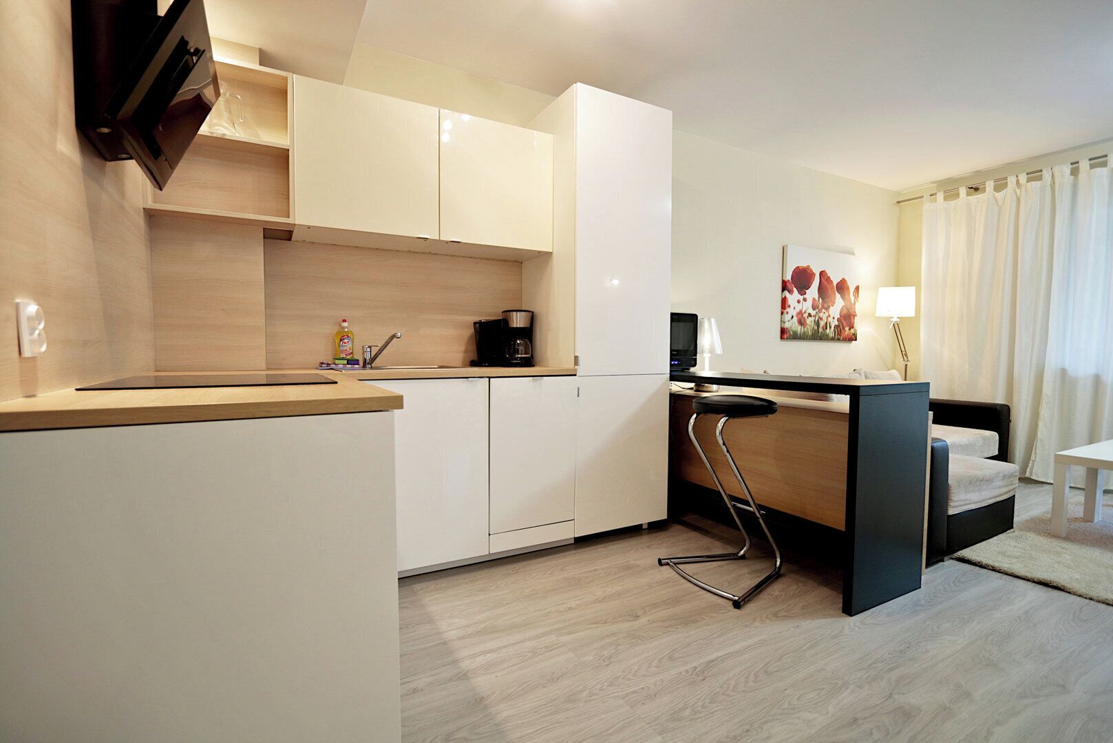 Une cuisine moderne avec des meubles blancs, une machine à café et un petit coin bar.