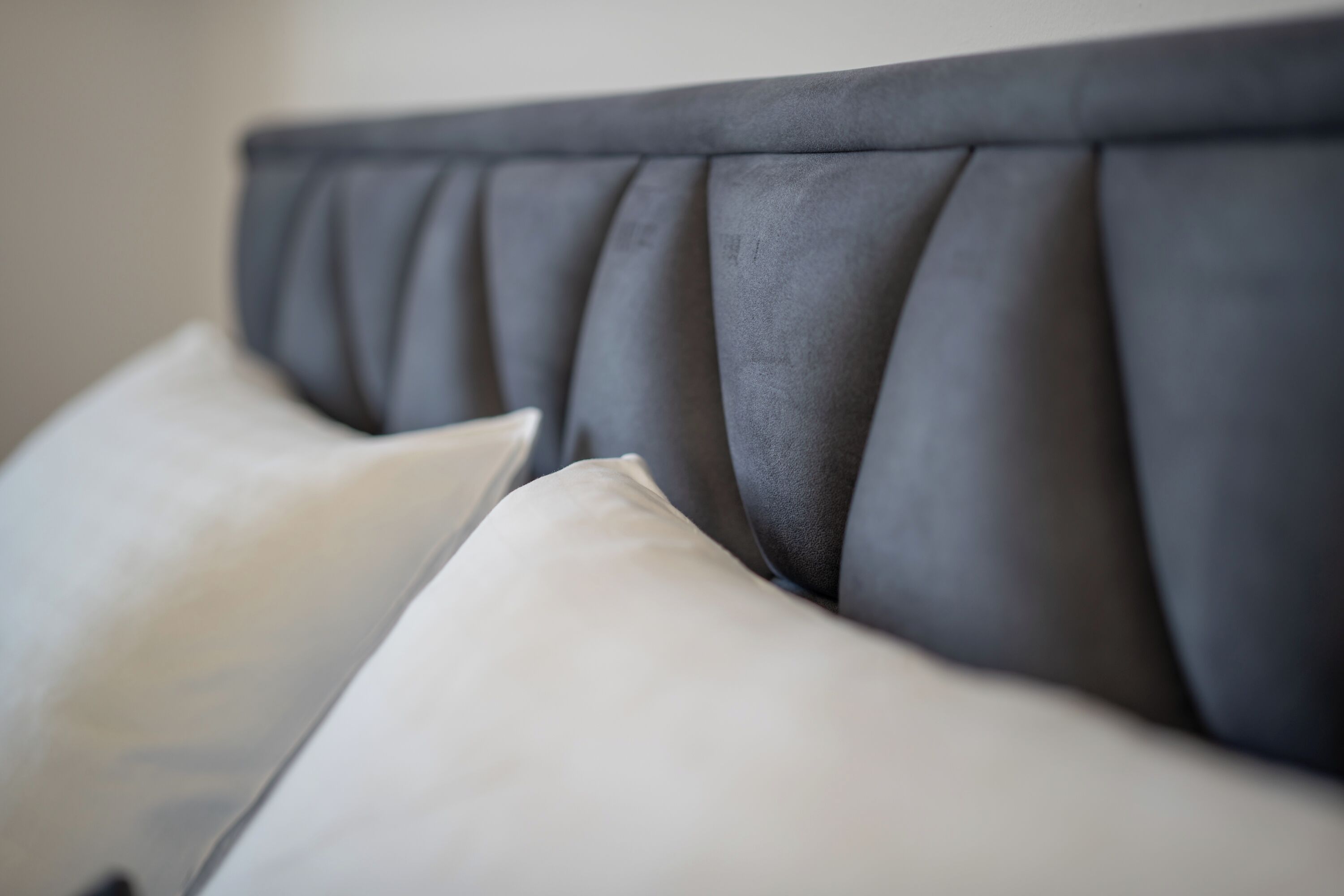 A close-up of a headboard with a tufted design and two pillows.