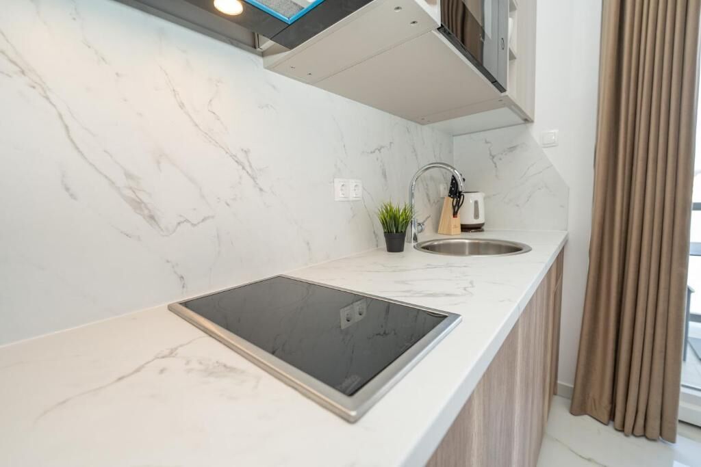 Una cocina moderna con encimera de mármol, estufa integrada y un lavabo.