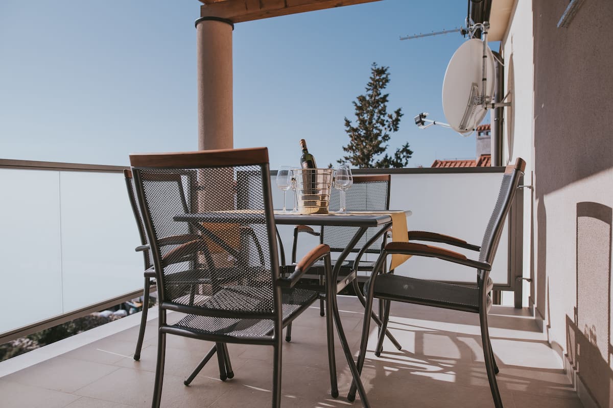 Un balcon avec une table et des chaises, une bouteille de champagne et une antenne parabolique.