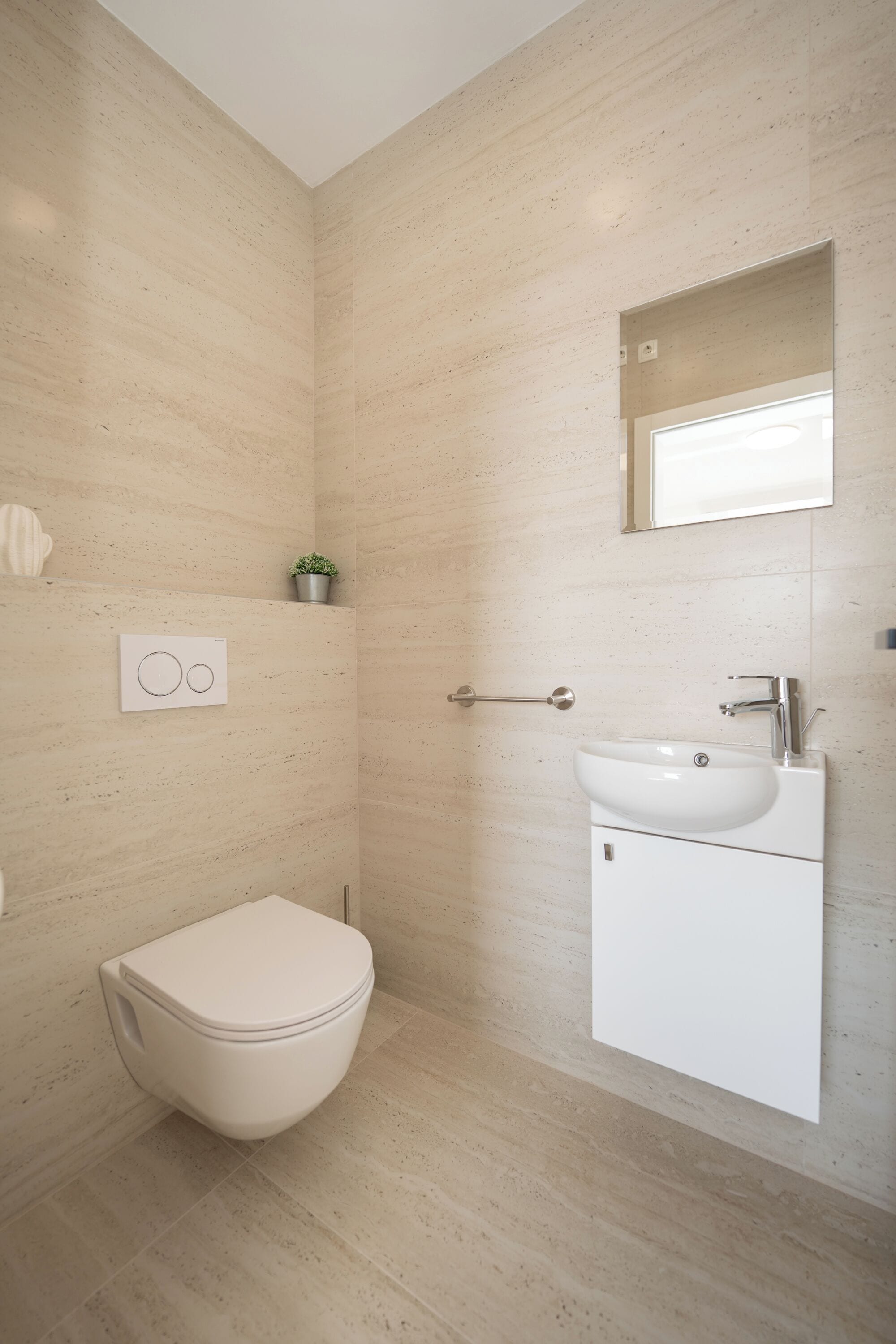 A modern bathroom with a toilet, sink, and mirror.