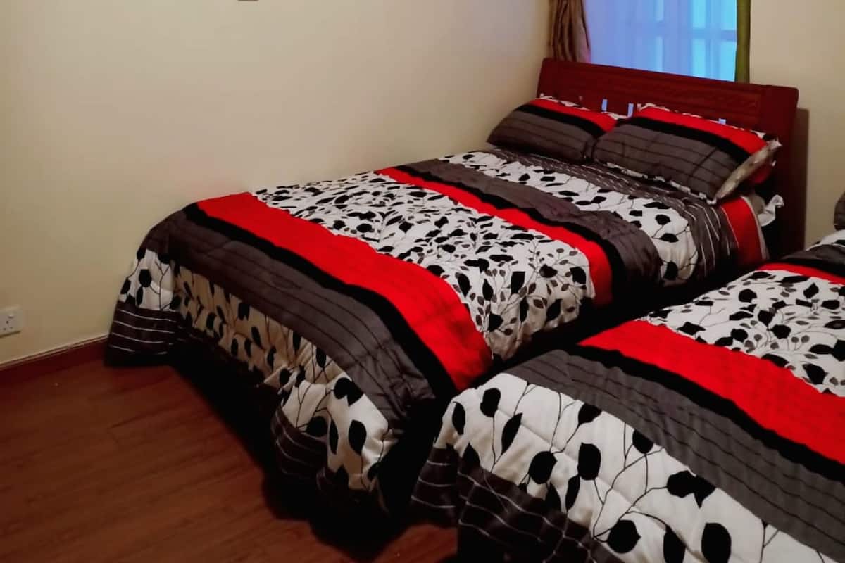 Un dormitorio con dos camas, una ventana con cortinas y dos cuadros en la pared.