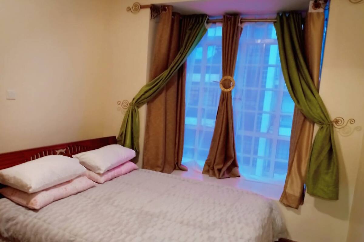 Habitación de hotel con cama, almohadas, cortinas y ventana con vistas.