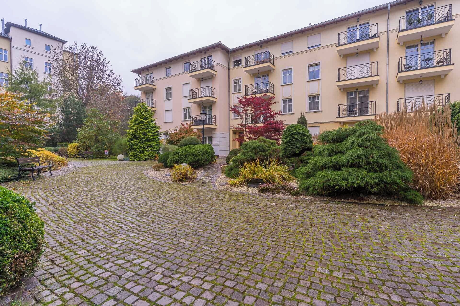 A courtyard with cobblestone paving, surrounded by multi-story buildings with balconies.