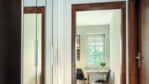 A hallway with a wooden door, a mirrored wardrobe, and a dining area with a table and chairs. - Imperial Apartments - Patio Mare (Sopot)