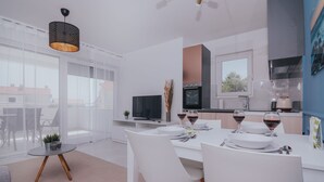 Een moderne keuken met witte kasten, een ingebouwde oven en een eethoek met een ronde tafel en witte stoelen.