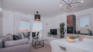 Een modern appartement met woonkamer, eethoek, keuken en balkon.