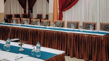 Un salón de conferencias con una larga mesa, sillas y botellas de agua.