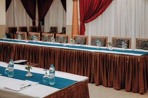 Un salón de conferencias con una larga mesa, sillas y botellas de agua.