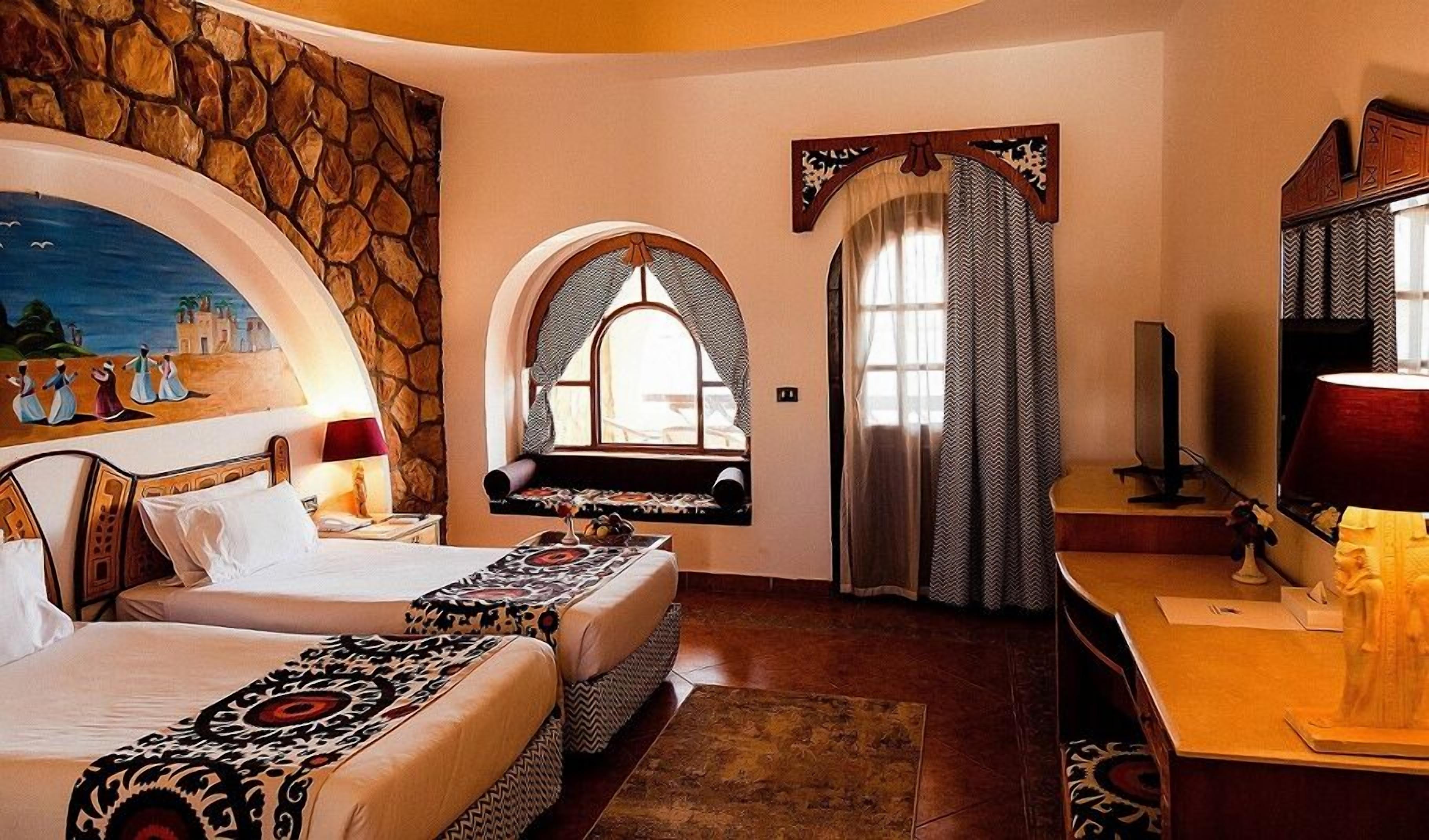 A room with two beds, a stone wall, a mural, a window with a view, and a television.