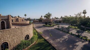 A courtyard with stone buildings, palm trees, and a central garden area.