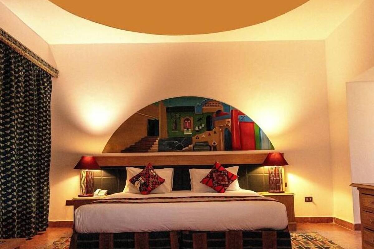 A bedroom with a large bed, a headboard with a mirror, and two bedside lamps.