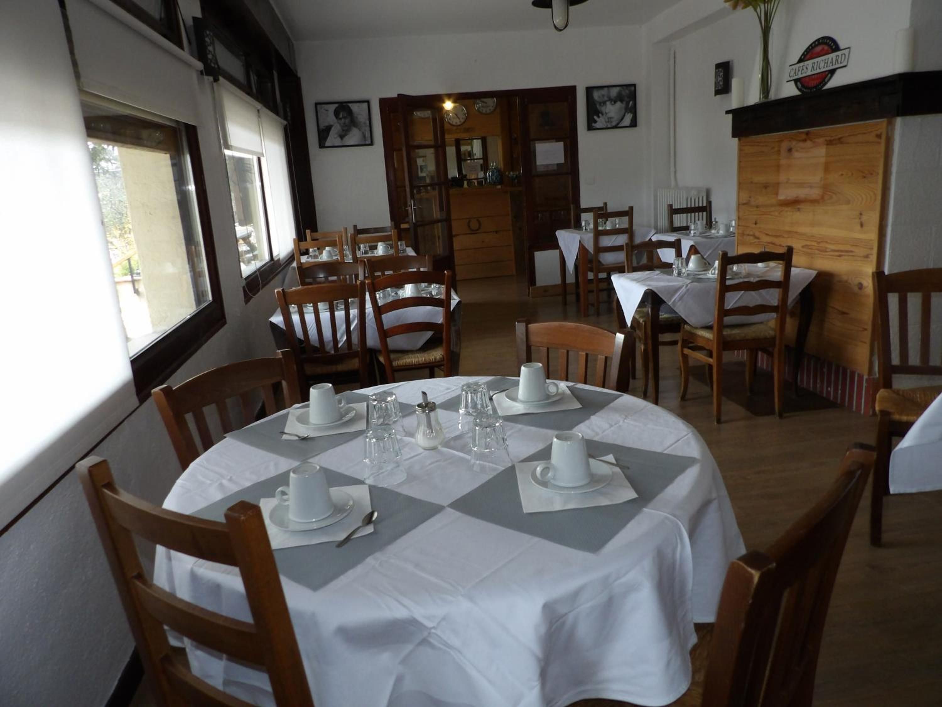 Zona pranzo con tavoli rotondi, sedie e tovaglie bianche.