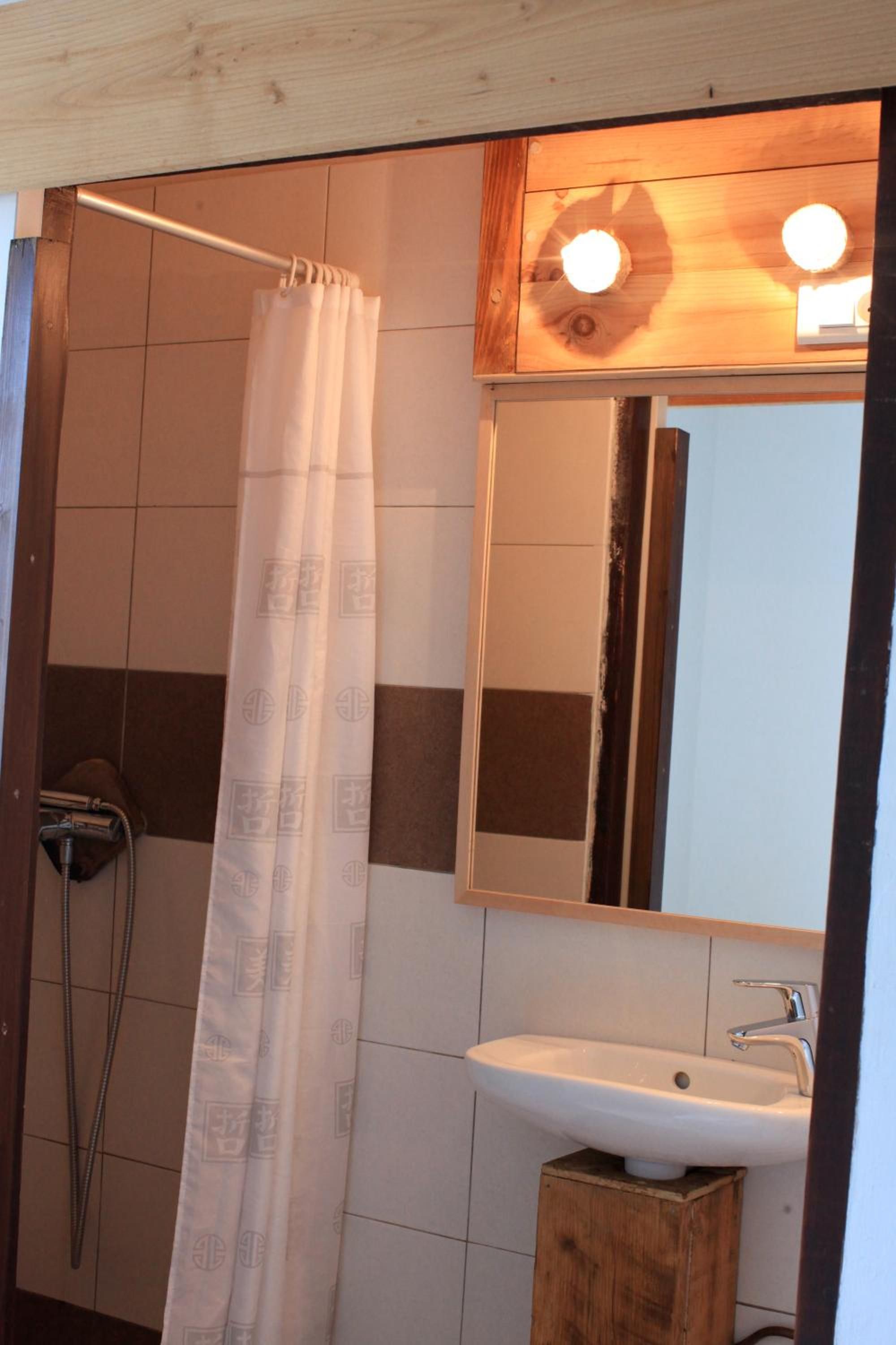 A bathroom with a shower curtain, a sink, and a mirror.