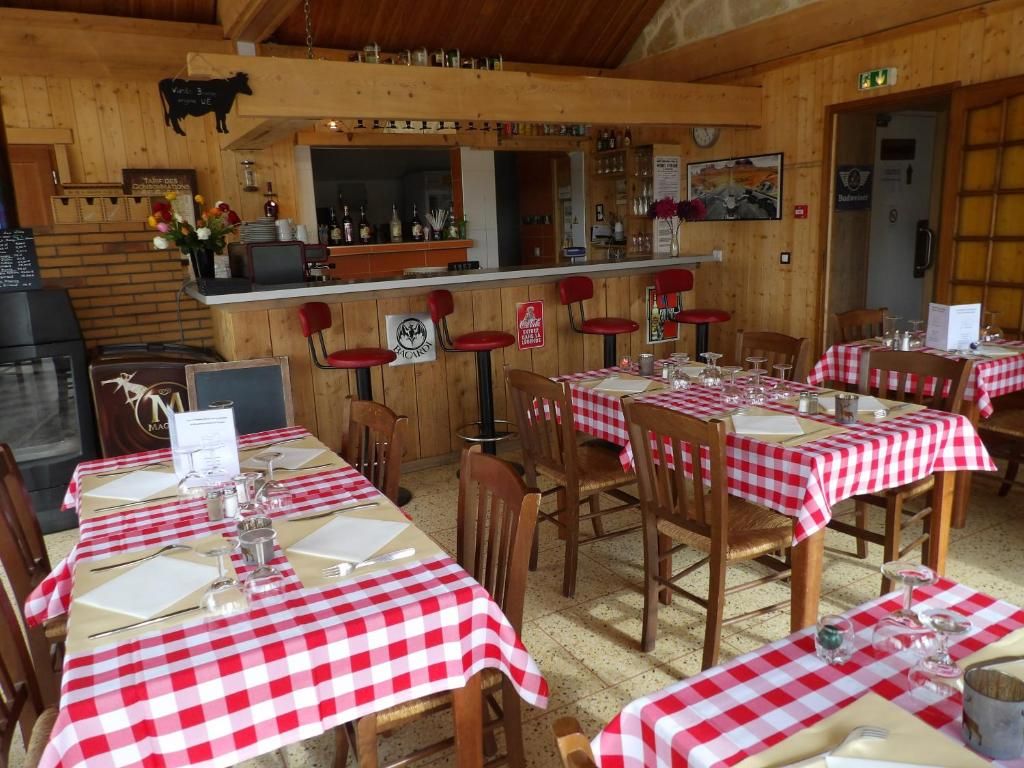 A restaurant with wooden interior, red and white checkered tablecloths, and a bar area.