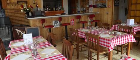 A restaurant with wooden interior, red and white checkered tablecloths, and a bar area.