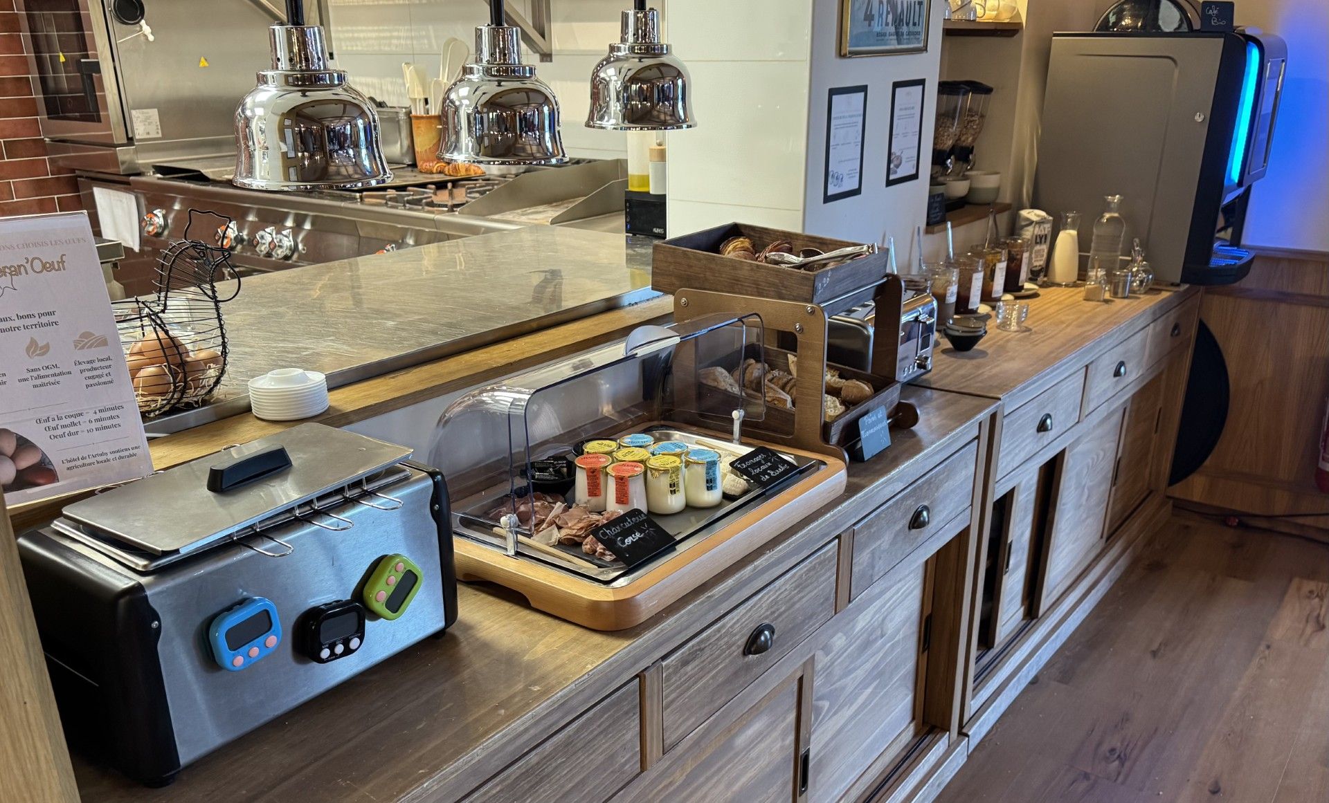 A café counter with a coffee machine, a display of pastries, and a menu sign.
