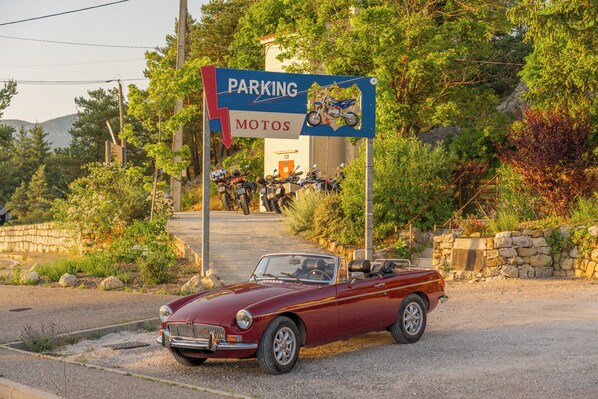 A red convertible parked in front of a sign indicating a parking area for motorcycles. - Logis Hôtel de l'Artuby (Séranon)