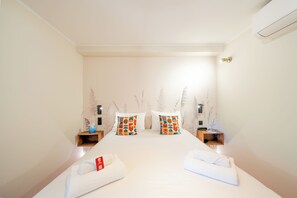 Una habitación de hotel con una cama grande, dos mesitas de noche, un aire acondicionado instalado en la pared y decoración en la pared.