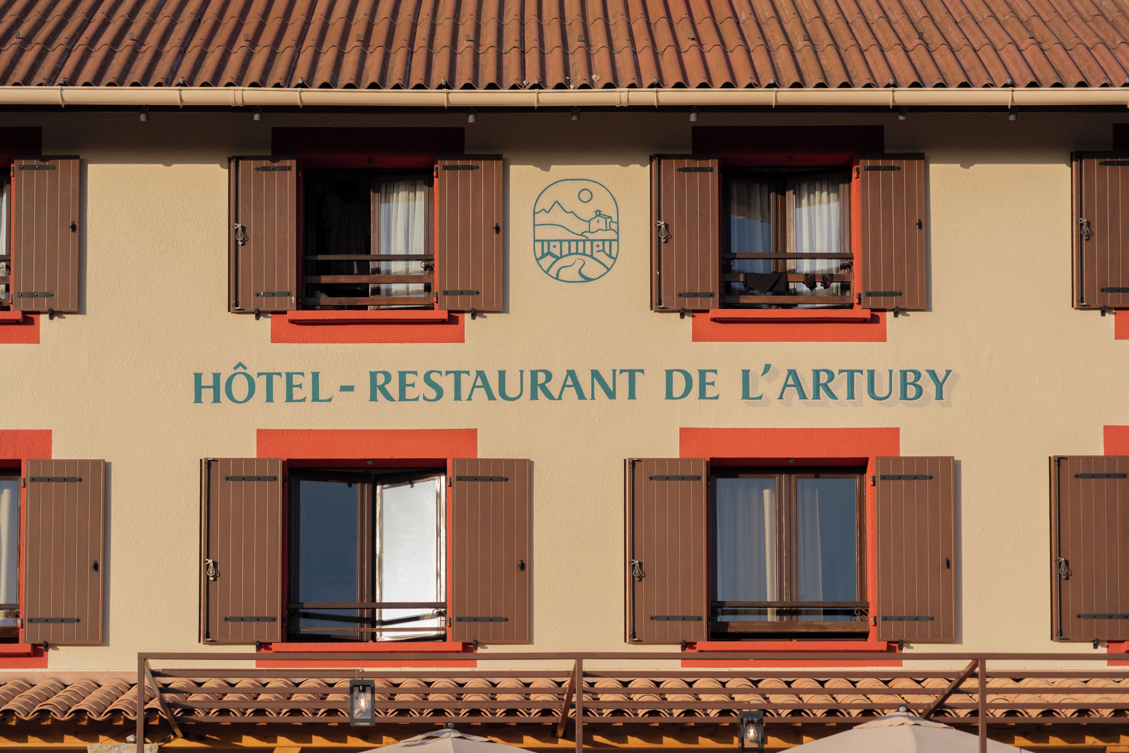 Un bâtiment portant l’enseigne « Hôtel-Restaurant de l’Artuby » et doté de nombreuses fenêtres avec volets.