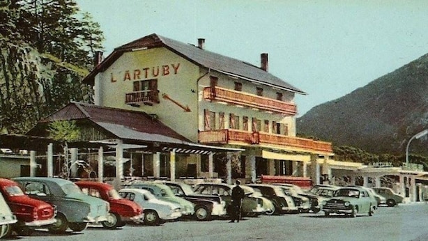 Un edificio con la leyenda 'L'ARTUBY' y una fila de coches aparcados en la parte delantera.
